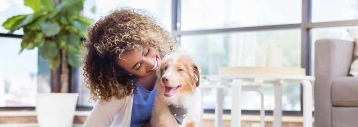Woman cuddling a dog in a bright living room